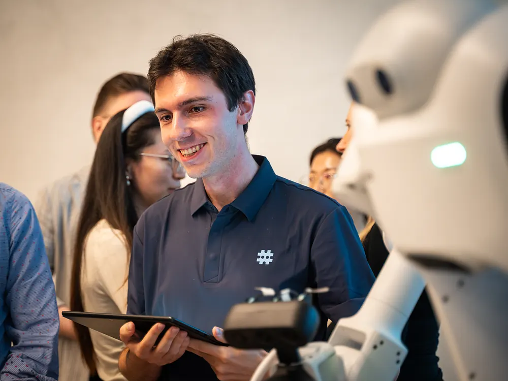 A sudo team member with a tablet among visitors beside the sudo robot