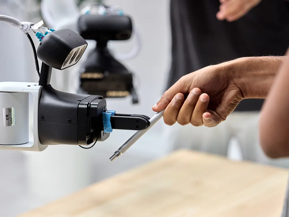 A visitor handing a pen to the sudo robot's gripper